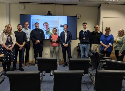 Photo of a group of researchers smiling at the camera in a meeting room