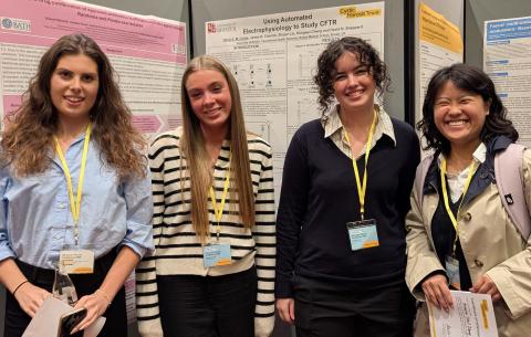 Group photo of four women by science displays at a conference