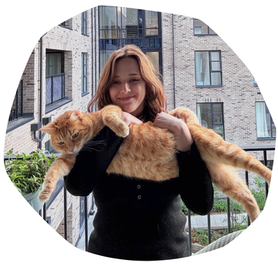 Margot, a young woman with long reddish-brown hair, holding a large ginger cat