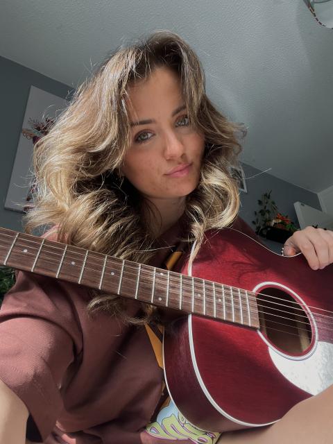 Abi sits with a guitar on her lap