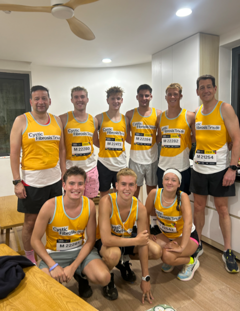 a group of 9 people wearing cystic fibrosis vests smiling
