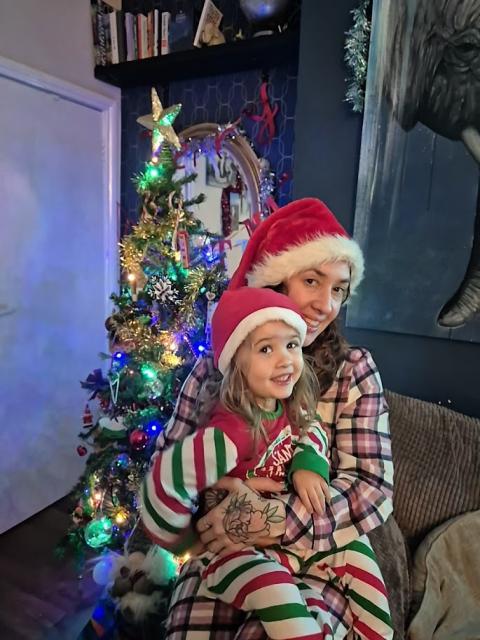 Kim and Ana, who has CF, both dressed in Christmassy outfits with a Christmas tree behind them