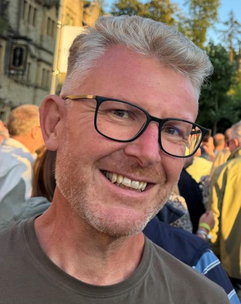 Nick Elliott, a smiling man with grey hair and glasses