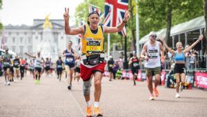 A man running in the London marathon, wearing a yellow Cystic Fibrosis Trust vest