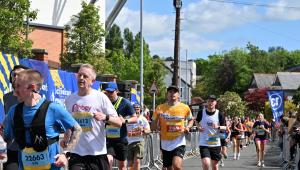A man running wearing a yellow Cystic Fibrosis Trust top