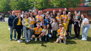 a group of people celebrating and cheering in yellow cystic fibrosis trust tops