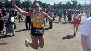 lady in cystic fibrosis trust yellow vest jumping in the air with her medal 