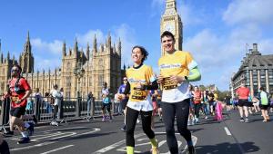 a man and woman running over the streets of London in a yellow cystic fibrosis trust top