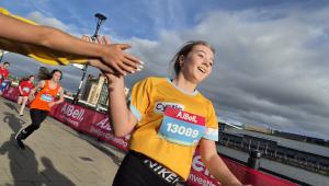 lady wearing a cystic fibrosis trust top running and high fiving a supporter