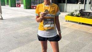 lady smiling wearing a yellow cystic fibrosis trust top, holding her race medal